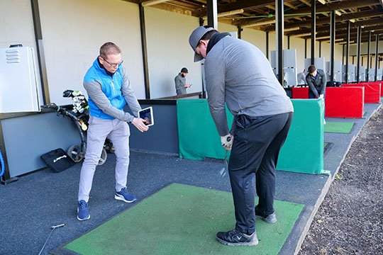 Mark Haines giving a golf lesson in a driving range